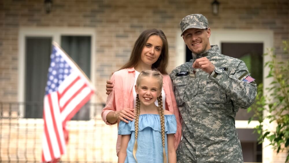 An American military family posing with keys to their new home purchased with VA loan assistance